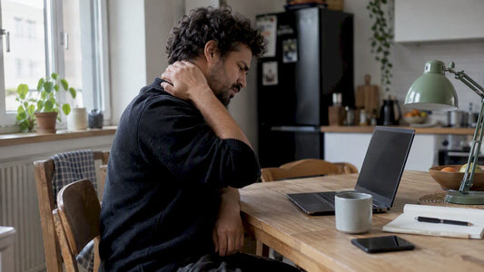 Travailleur en télétravail, épuisé, la nuque raide devant son ordinateur